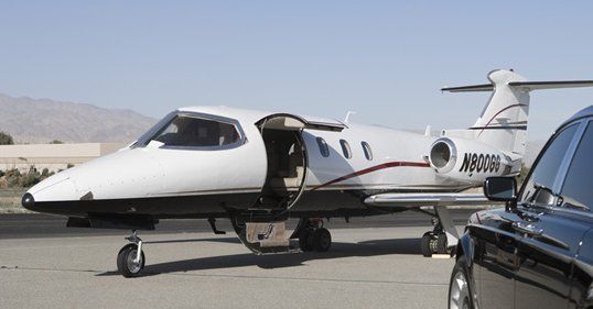 Black Limousine near private jet at airport